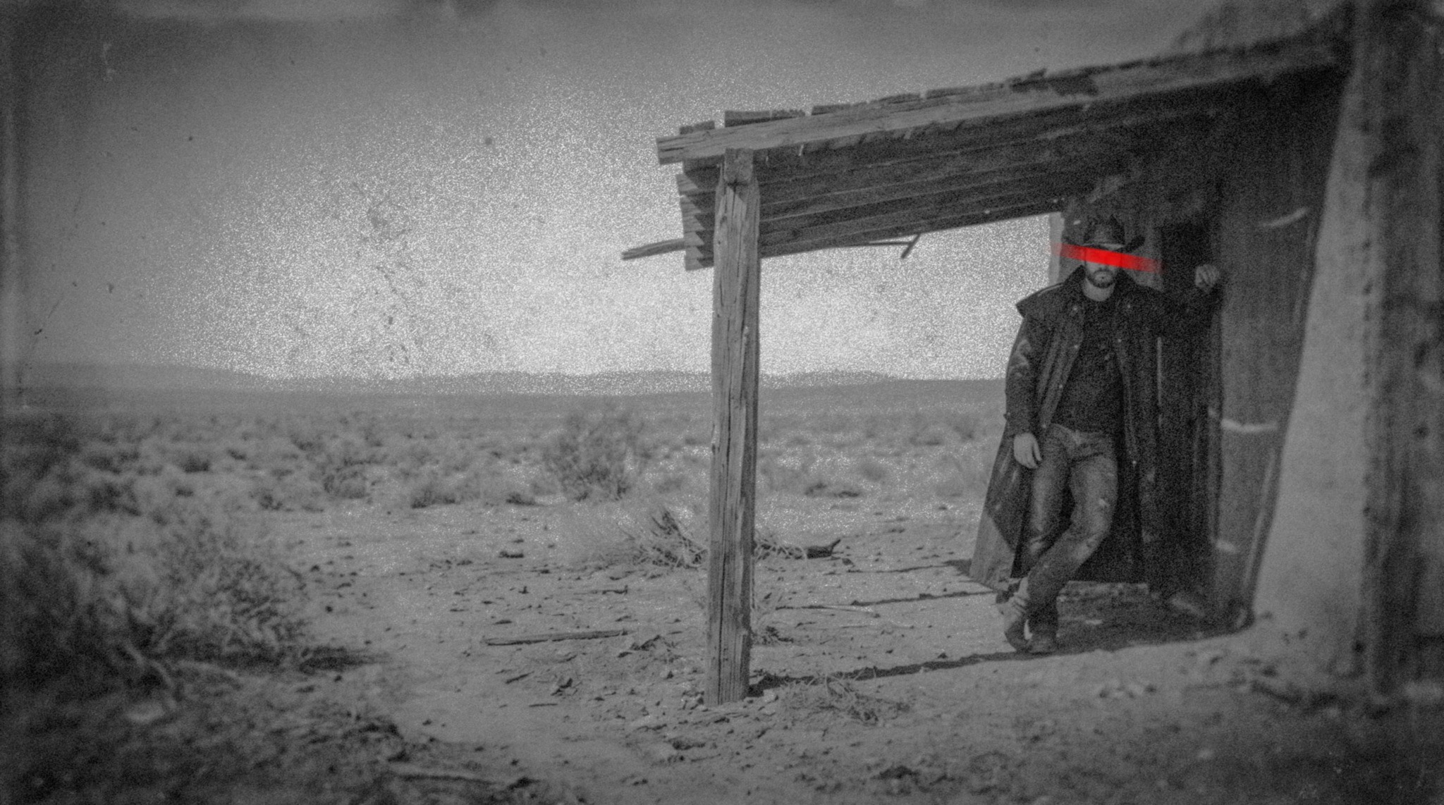 Lone outlaw at a wooden shelter in a vast desert
